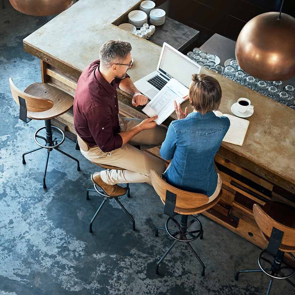 Mies ja nainen istuu kahvilla ja lukee uutisia tietokoneelta