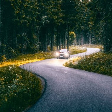 Auto ajaa metsäisellä tiellä Ruotsissa