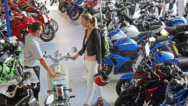 Nainen juttelee myyjän kanssa moottoripyöräliikkeessä