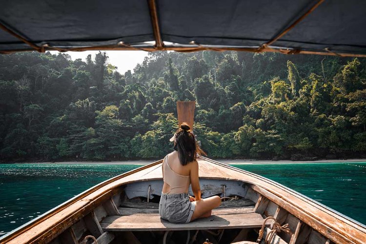 nainen istuu veneen keulassa thaimaassa