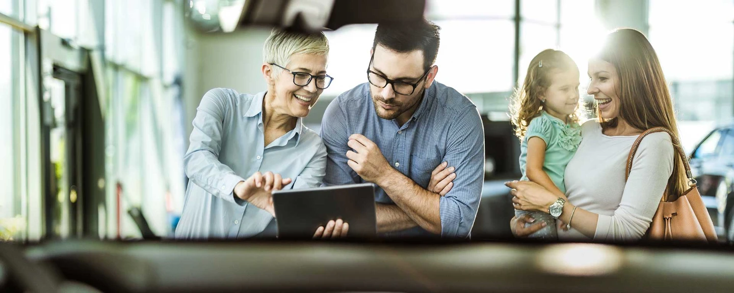 Perhe valitsee autoa autokaupassa myyjän kanssa