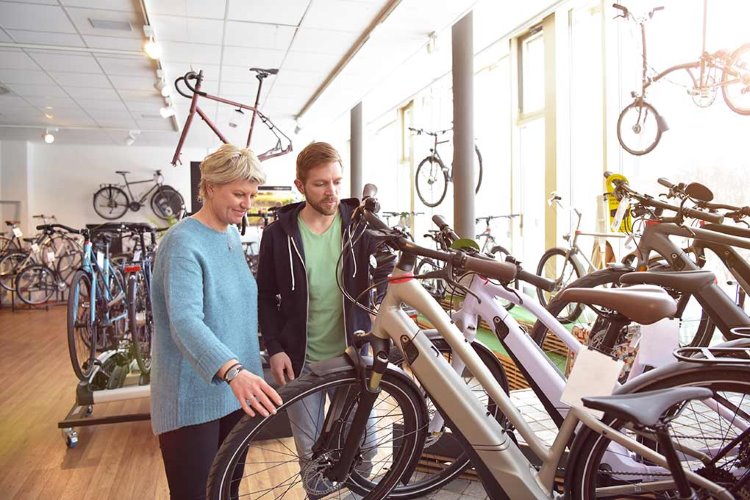 Nainen ja mies tutkailee sähköpyörää polkupyöräkaupassa