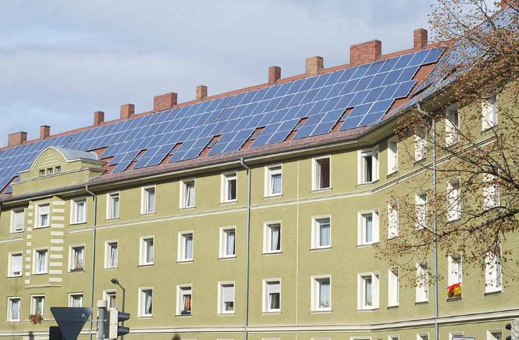 Vihreän kerrostalon katolla on paljon aurinkopaneeleita